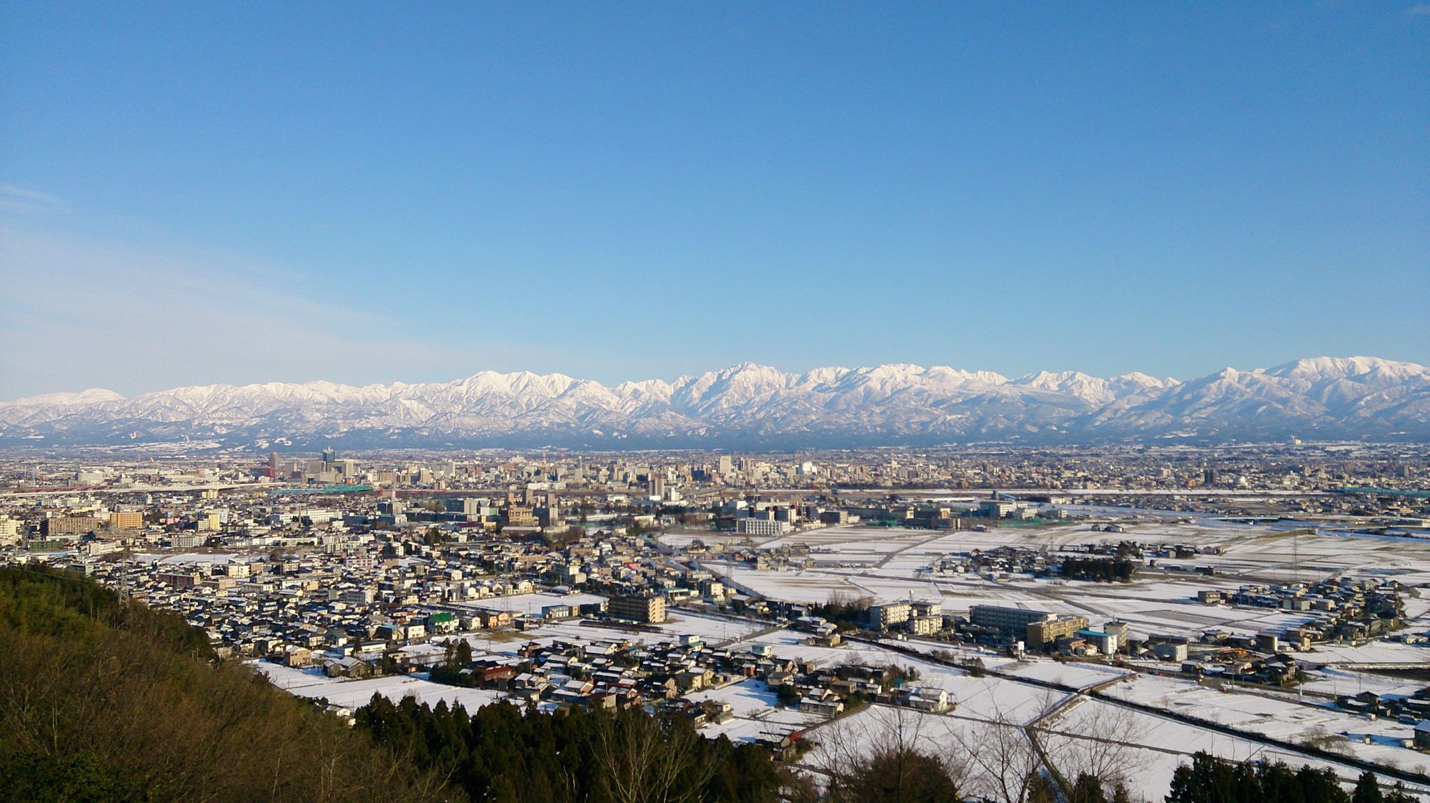 雪をいただく立山連峰と富山の街並み